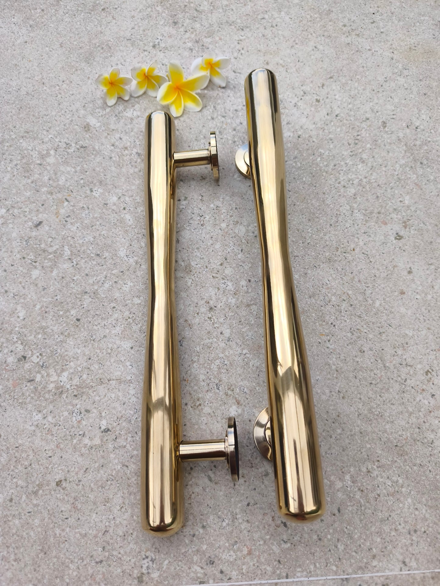 Solid brass door pull pair standing upright with mounting posts visible, gold polished barn door and gate handles in a tapered bar style