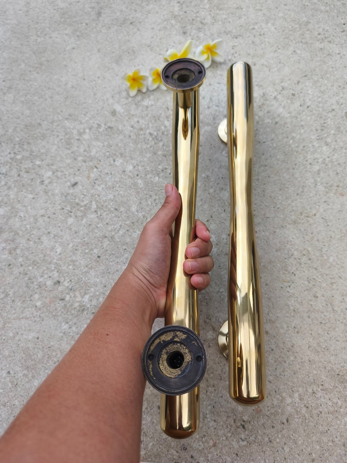 Brass door pull handle held up to show the mounting posts and screw fittings, solid brass gold door hardware that attaches with screws
