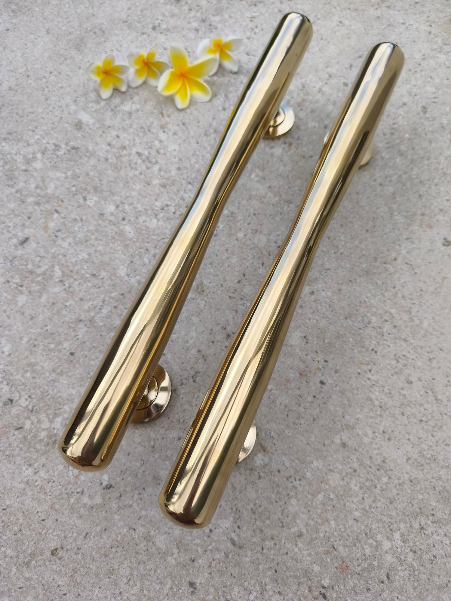 Close up of a pair of gold brass door pull handles, shiny polished solid brass hardware for contemporary, rustic and classic home entrances