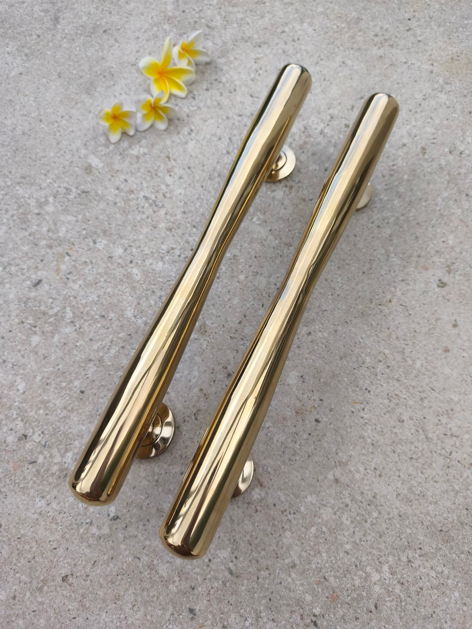 Diagonal view of two solid brass door pull handles, large polished gold door pulls for main doors, garden gates and rustic barn doors