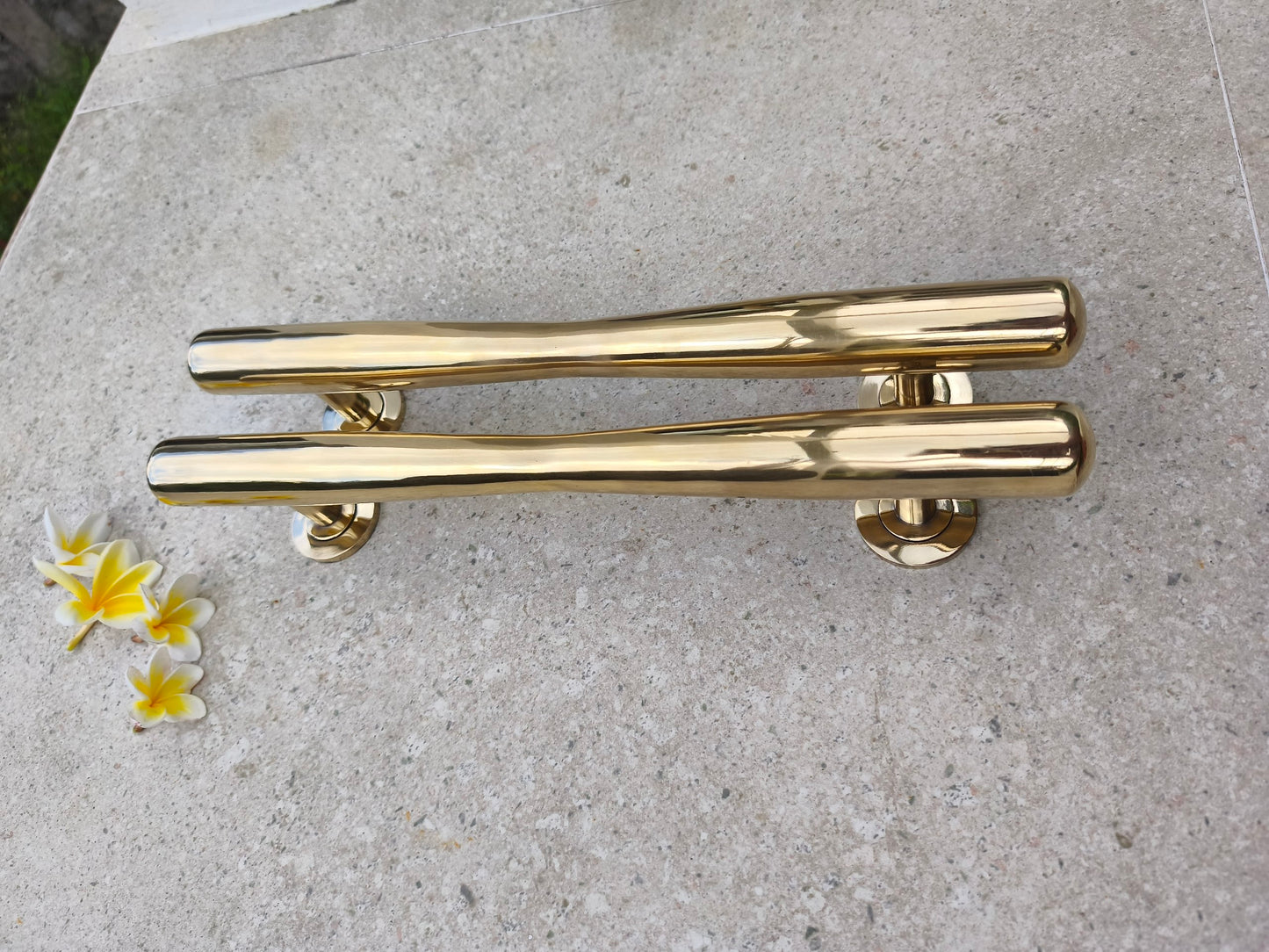 Close up side view of a pair of polished brass door pulls, gold solid brass handles with mounting posts for entry doors and double doors