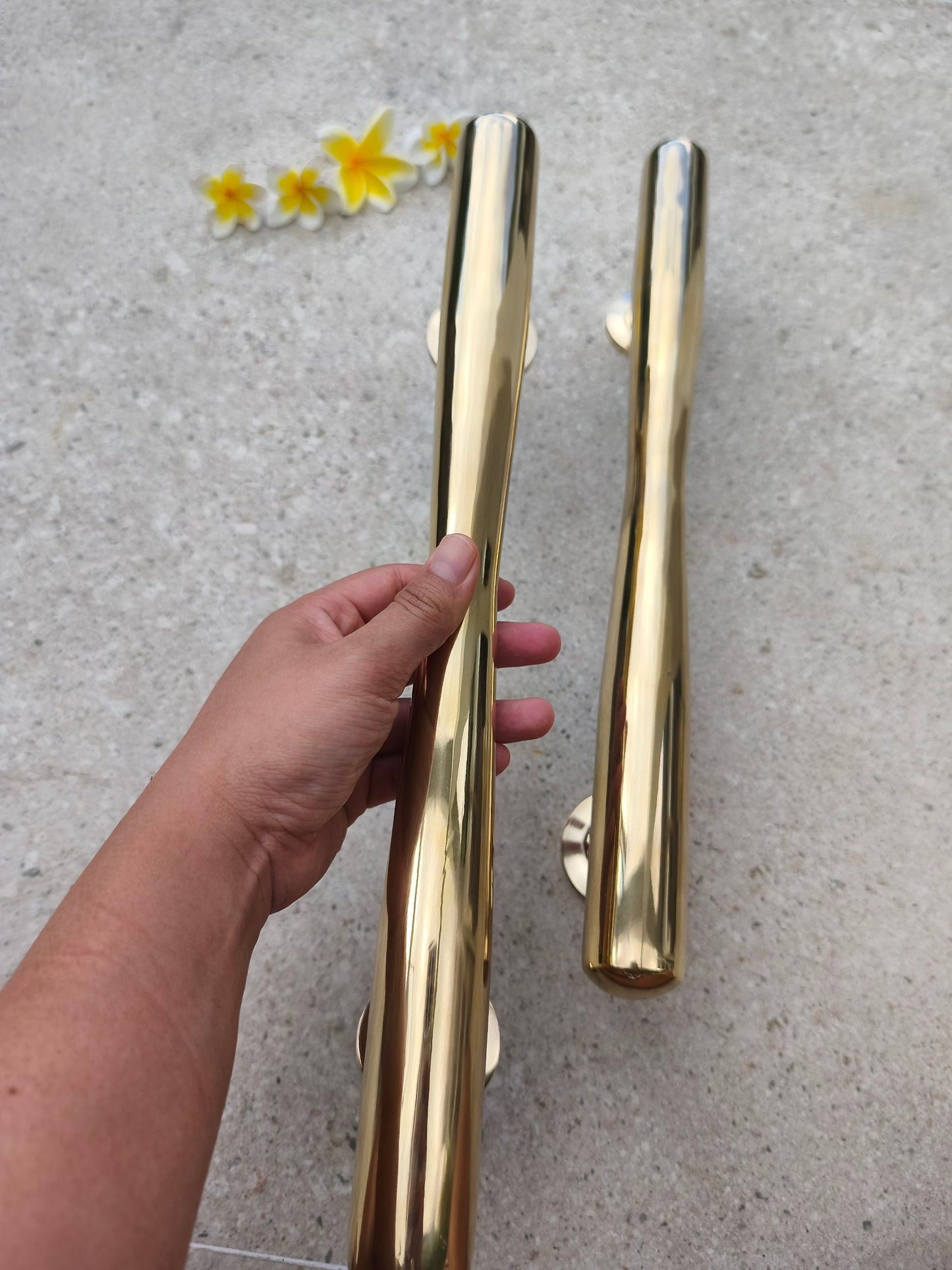 Hand holding a 40 cm solid brass door pull to show its size, large gold entry door handle with a smooth tapered grip for main doors and gates
