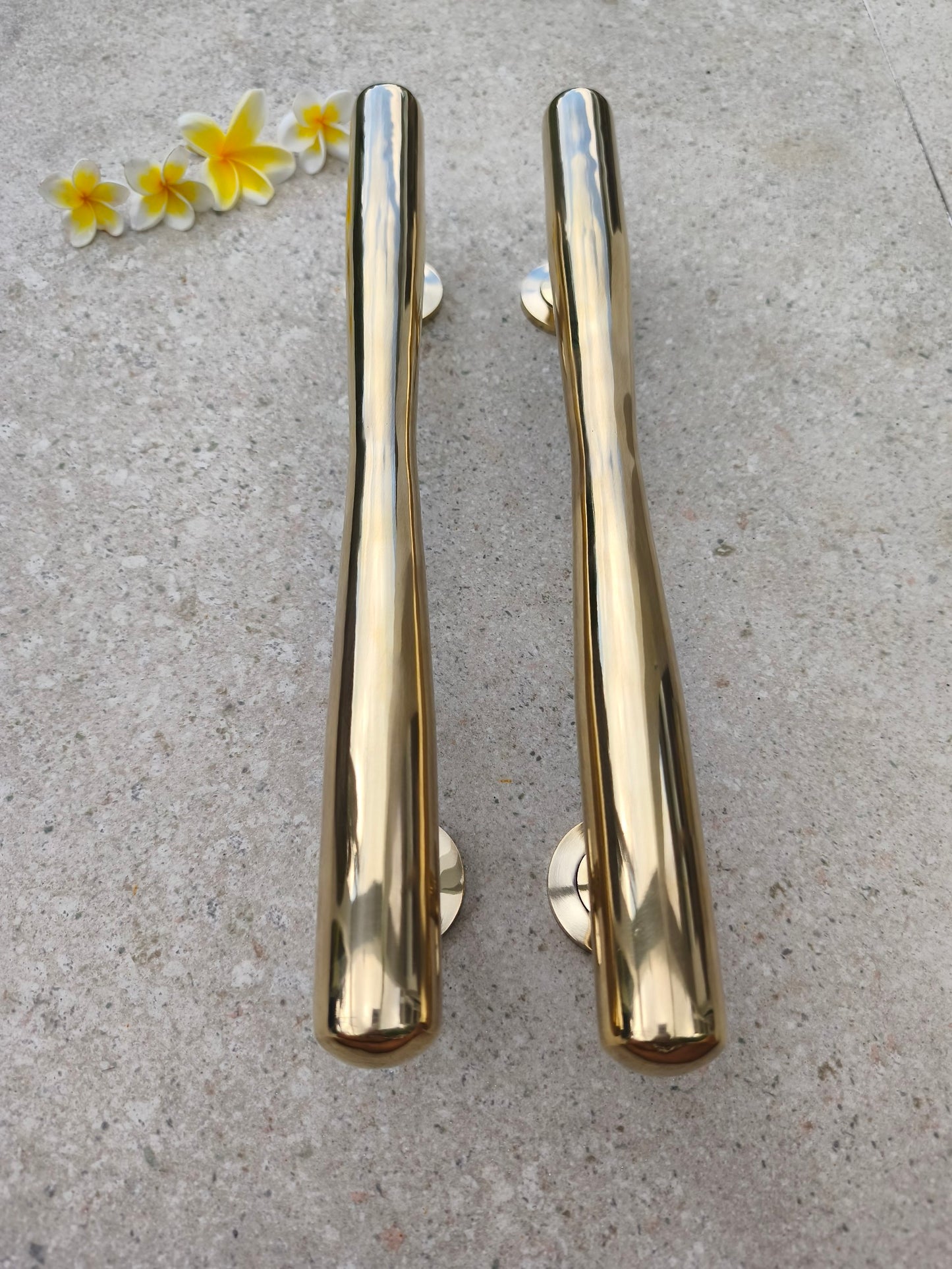 Front view of two polished gold brass door pulls, long tapered bar handles for modern and classic entrance doors, wooden doors and double doors